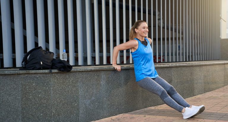 Full length shot of joyful sportive middle aged woman in sportswear having workout outdoors