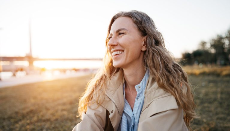 Happy young woman sitting on lawn outdoors in the city
